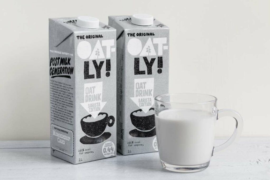 Un carton de lait d'avoine à côté d'un verre de lait d'avoine.