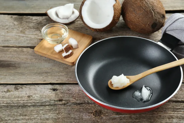 Huile de coco sur une cuillère en bois dans une poêle.