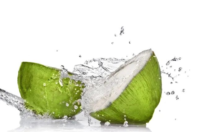 Eau de coco sortant d'une noix de coco verte fraîche.